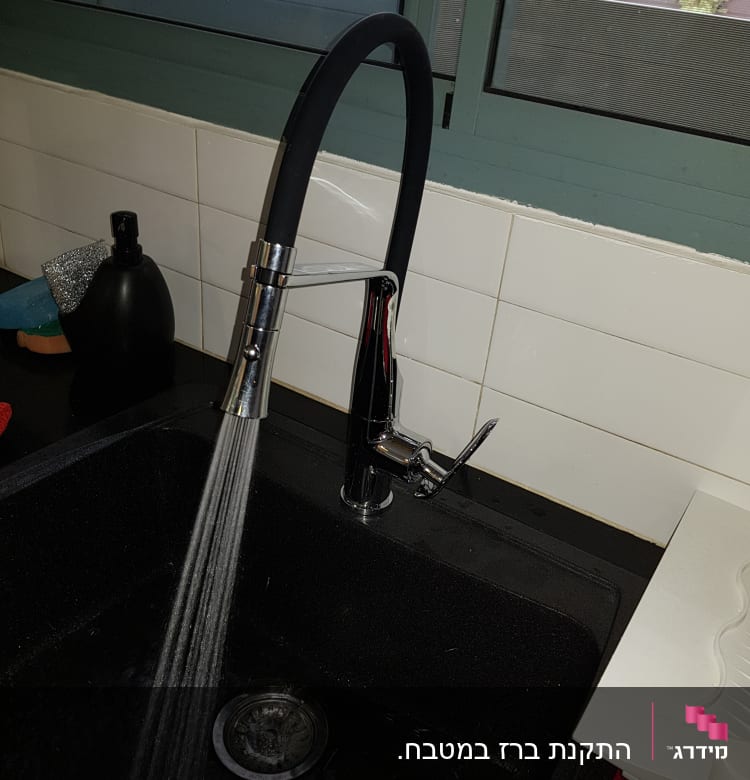 ברז מטבח עם מים זורמים לכיור שחור